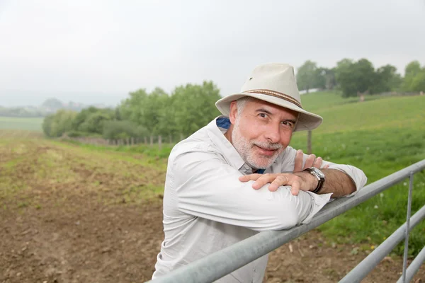 Farmář opřený o plot zemědělské půdy — Stock fotografie