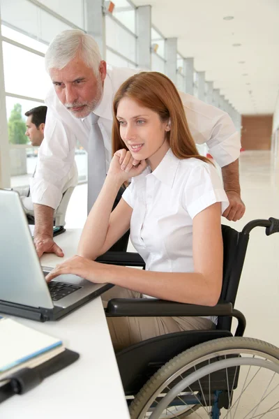 Woman in wheelchair with trainer in office — Stock Photo, Image