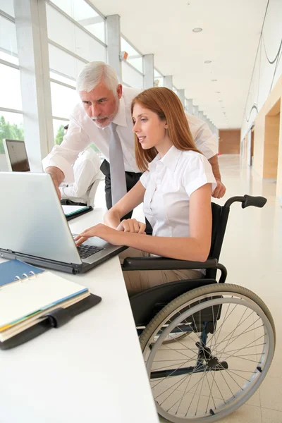 Γυναίκα σε αναπηρική καρέκλα με εκπαιδευτή στο γραφείο — Φωτογραφία Αρχείου