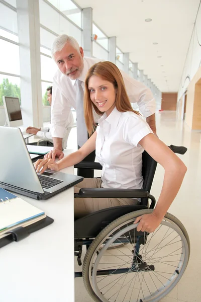 Γυναίκα σε αναπηρική καρέκλα με εκπαιδευτή στο γραφείο — Φωτογραφία Αρχείου