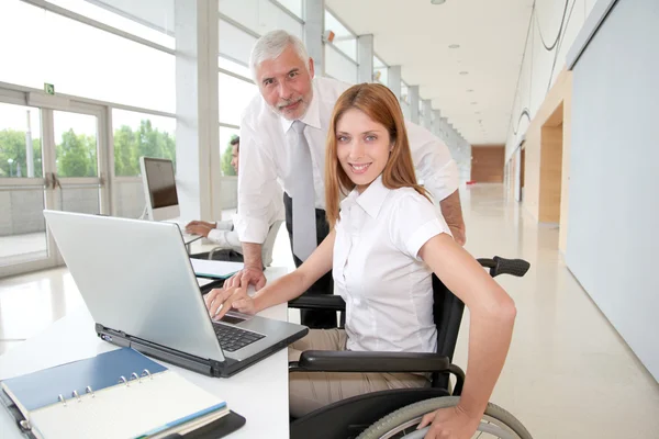 Женщина в инвалидной коляске с тренером в офисе — стоковое фото