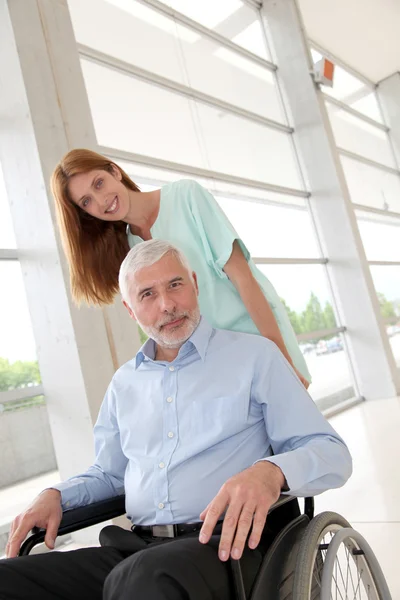 Verpleegkundige helpen senior man in rolstoel — Stockfoto