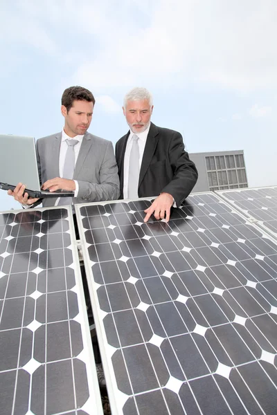 Negócios em pé por painéis solares — Fotografia de Stock