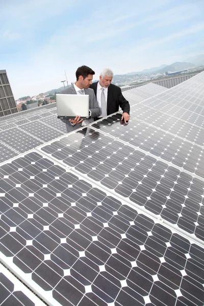 Empresário em pé junto aos painéis solares — Fotografia de Stock