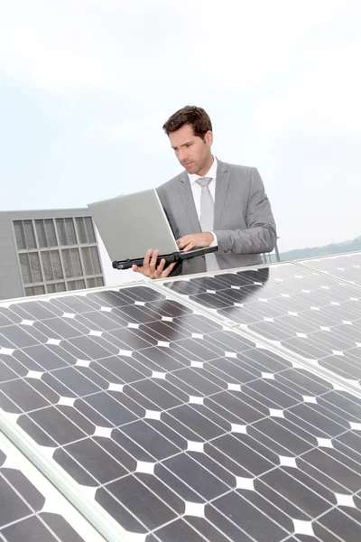 Empresário em pé junto aos painéis solares — Fotografia de Stock