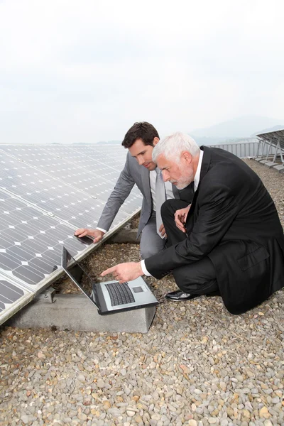 Empresários verificando painéis solares em execução — Fotografia de Stock