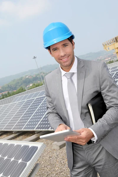 Бизнесмен, стоящий на установке солнечных панелей — стоковое фото