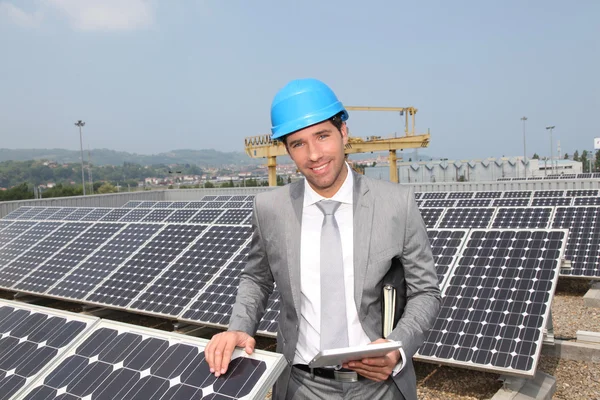 Бизнесмен, стоящий на установке солнечных панелей — стоковое фото