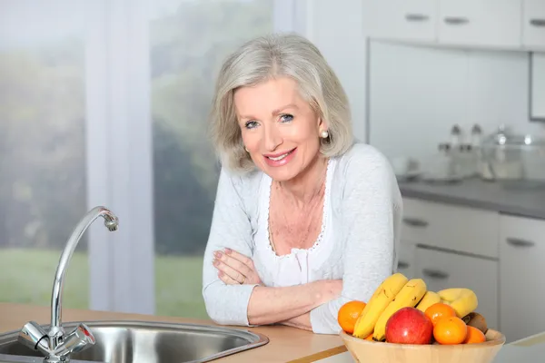 Äldre kvinna som står i köket — Stockfoto