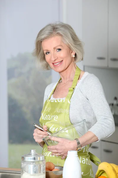 Крупный план улыбающейся пожилой женщины, выпекающей на кухне — стоковое фото