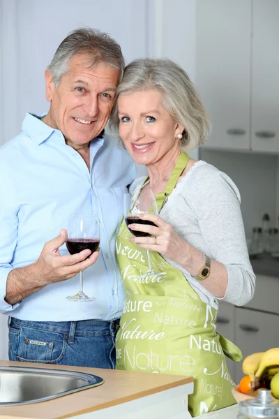 Pareja mayor bebiendo vino en la cocina — Foto de Stock