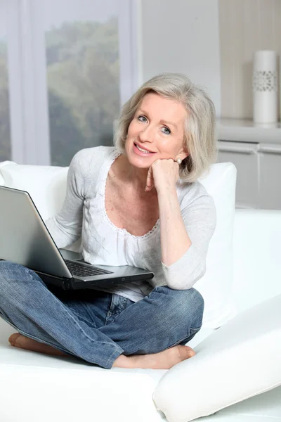 Senior vrouw zitten in de Bank met laptopcomputer — Stockfoto