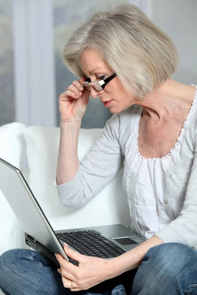 Старша жінка сидить в дивані з ноутбуком — стокове фото