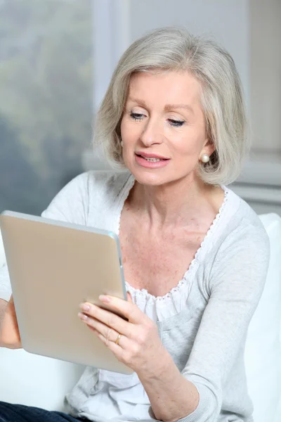 Zbliżenie starszy kobieta siedzi na kanapie z elektronicznych pad — Zdjęcie stockowe