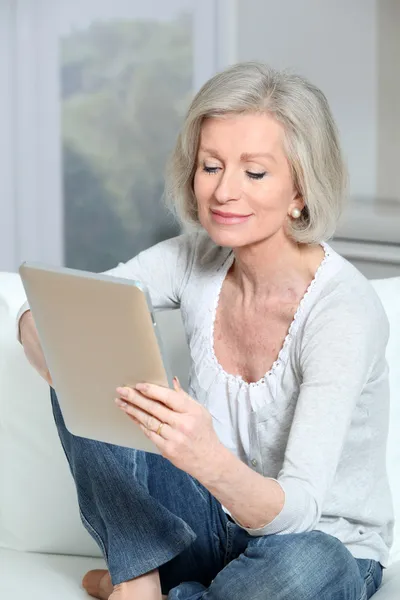 Zbliżenie starszy kobieta siedzi na kanapie z elektronicznych pad — Zdjęcie stockowe