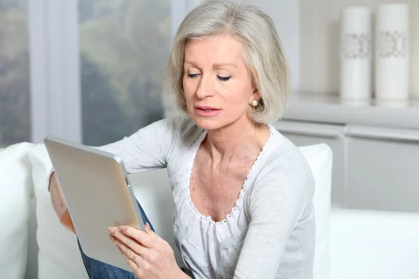 Closeup starší žena sedí na pohovce s elektronickým pad — Stock fotografie