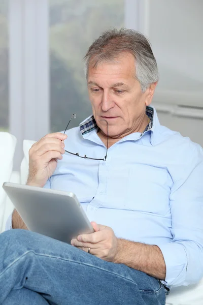 Senior man zit in Bank met elektronische tablet — Stockfoto