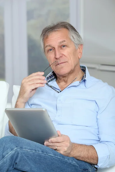 Senior man zit in Bank met elektronische tablet — Stockfoto