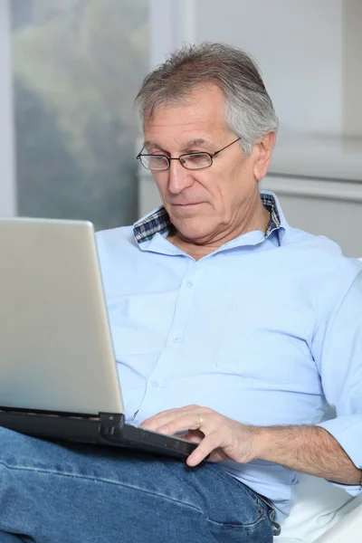 Starszy mężczyzna na kanapie z laptopem — Zdjęcie stockowe