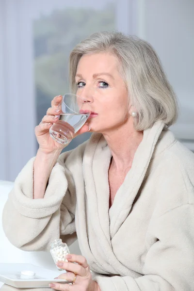 年配の女性の薬を飲んでバスローブ — ストック写真