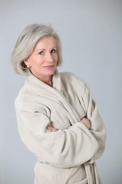 Старша жінка в халаті стоїть на білому тлі — стокове фото