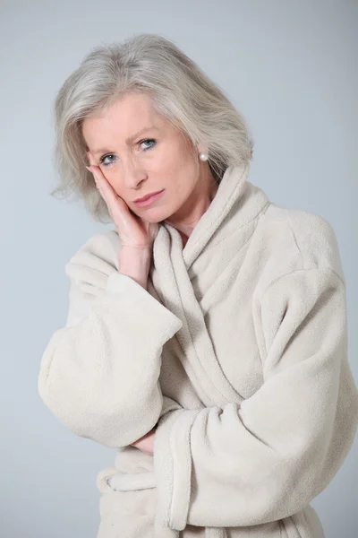 Старшая женщина в халате стоит на белом фоне — стоковое фото