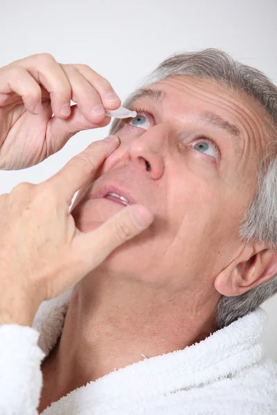 Senior mannen att sätta ögondroppar — Stockfoto