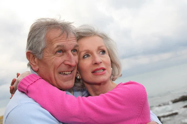 Lyckliga äldre par omfamnar varandra vid havet — Stockfoto