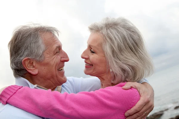 Счастливая пожилая пара, обнимающая друг друга у моря — стоковое фото