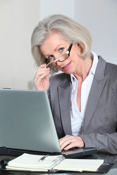 Старша бізнес-леді з окулярами, що працюють в офісі — стокове фото
