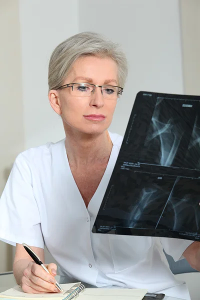 Retrato de enfermera madura sonriente en la oficina mirando rayos X —  Fotos de Stock