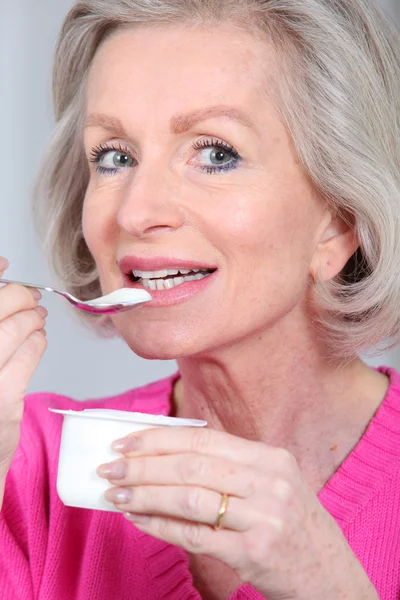 Porträtt av äldre kvinna äta yoghurt — Stockfoto