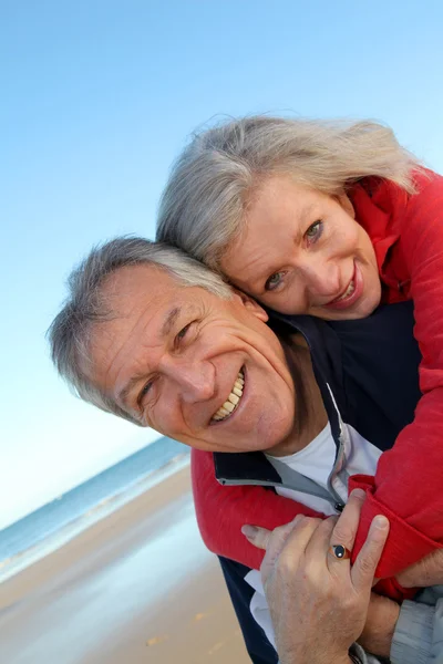 Senior Mann gibt Huckepack-Fahrt zu Frau am Meer — Stockfoto