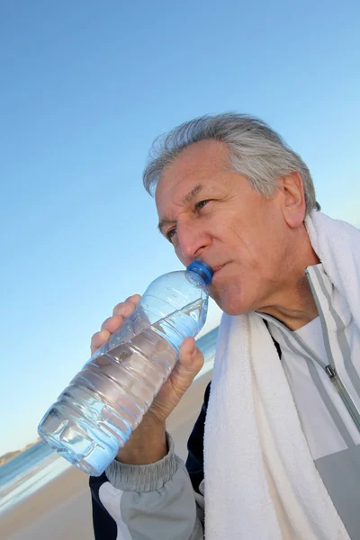 :Aktív vezető ivóvíz palack a strandon — Stock Fotó