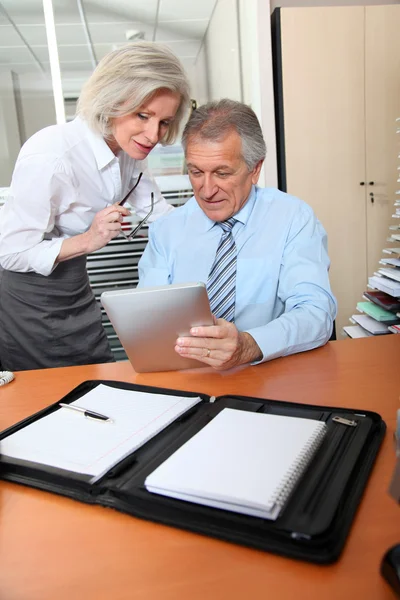 Negócios seniores no escritório com almofada eletrônica — Fotografia de Stock