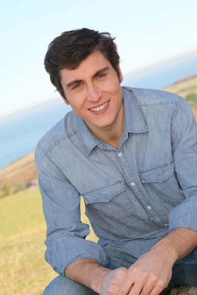 Portrait of smiling handsome man sitting in country field — Stock Photo, Image