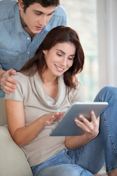 Jeune couple utilisant une tablette électronique à la maison — Photo