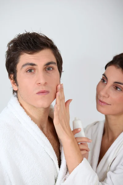 Mujer aplicando crema hidratante en la mejilla del novio —  Fotos de Stock