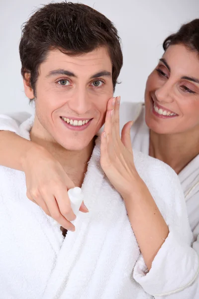 Mujer aplicando crema hidratante en la mejilla del novio — Foto de Stock