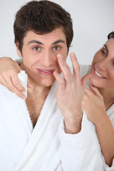 自分の顔の保湿剤を適用する若い couopke — ストック写真