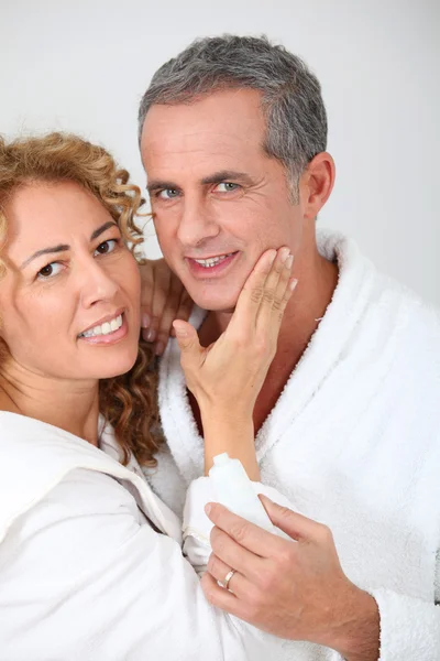 Женщина наносит увлажняющий крем на щеку своего парня — стоковое фото