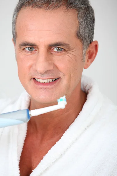 Porträtt av mogen man med hjälp av elektrisk tandborste — Stockfoto