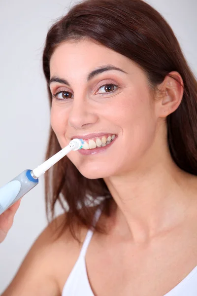 Ung kvinna borsta hennes tänder med elektrisk tandborste — Stockfoto