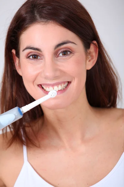 Elektrikli diş fırçası ile dişlerini fırçalama genç bir kadın — Stok fotoğraf
