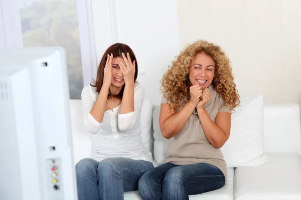 Flicka vänner tittar på en läskig film på TV — Stockfoto