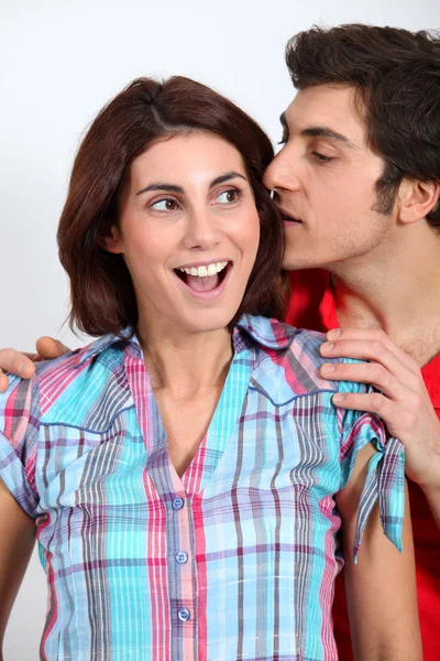 Молодой человек шепчет своей девушке на ухо — стоковое фото