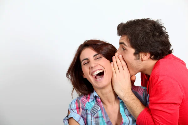 Jonge man in zijn vriendin oor fluisteren — Stockfoto