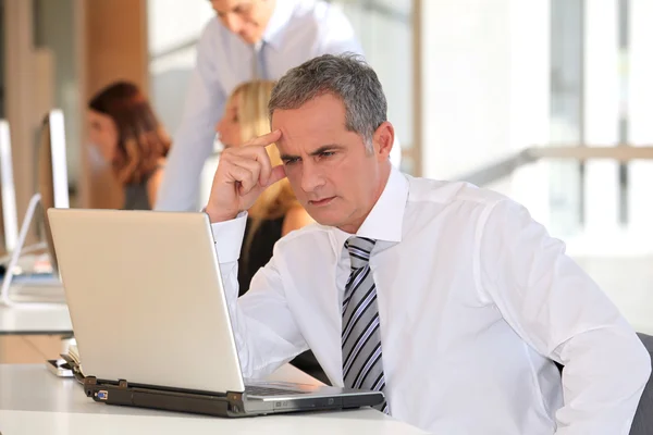 Volwassen zakenman die op laptopcomputer werkt — Stockfoto