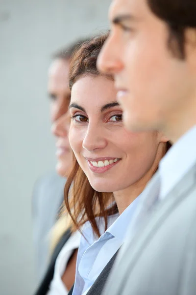 Glimlachende zakenvrouw permanent onder een groep — Stockfoto