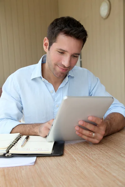 Uomo che lavora a casa con tablet elettronico Fotografia Stock